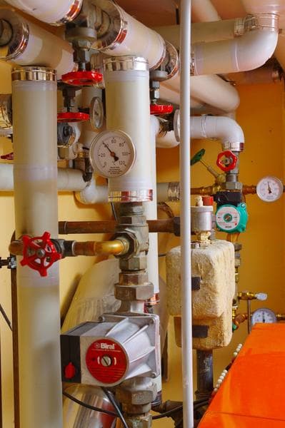 Industrial pipes, pressure gauges, and valves in a vessel engine room